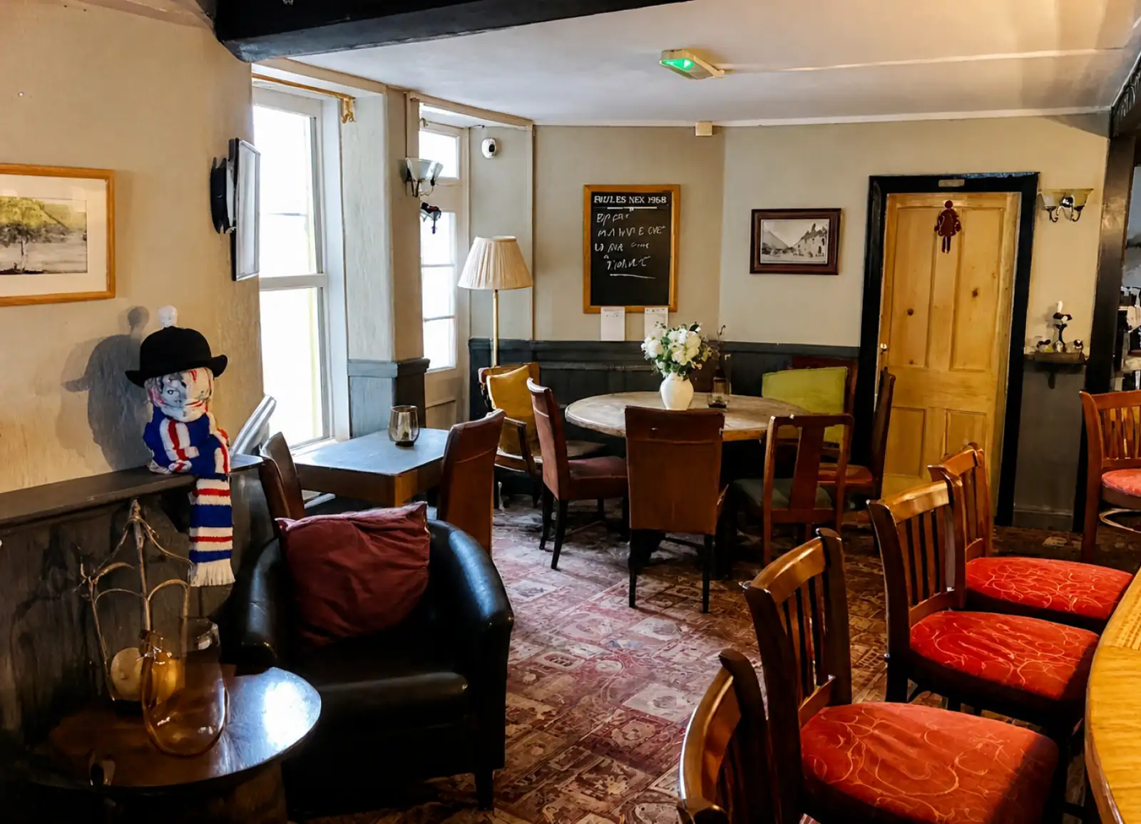 Lounge area inside The Pack Horse Inn with armchairs, tables and a blackboard
