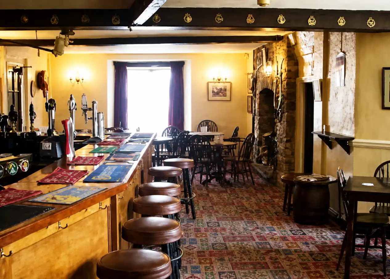 The bar counter with beer taps, stools and beamed ceiling